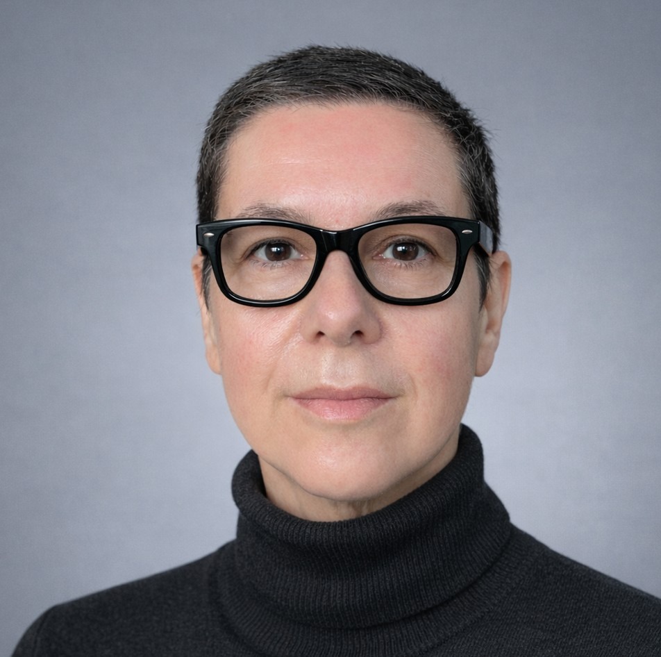 A headshot of Professor L. Monika Moskal. She wears a black turtleneck and black glasses and is against a light grey background.